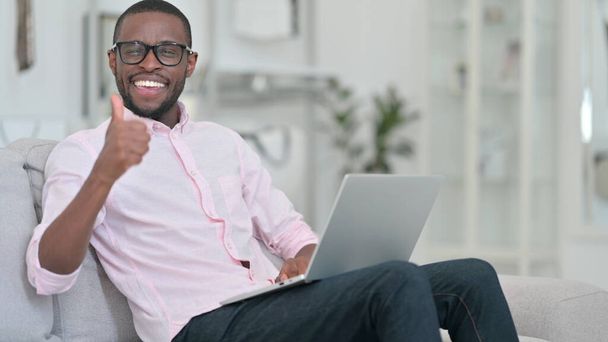 Polegares para cima por homem africano com laptop em casa  - Foto, Imagem