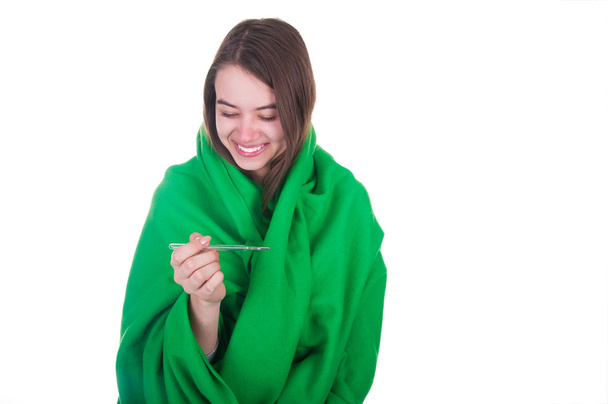 Жінка, вкрита ковдрою, тримає термометр у руці
 - Фото, зображення