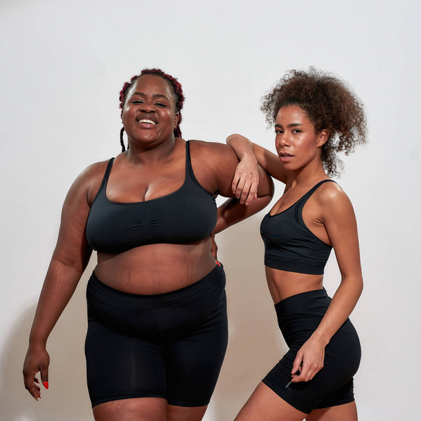 Couple of black women with different skin shade standing sexy in black tops - Photo, image