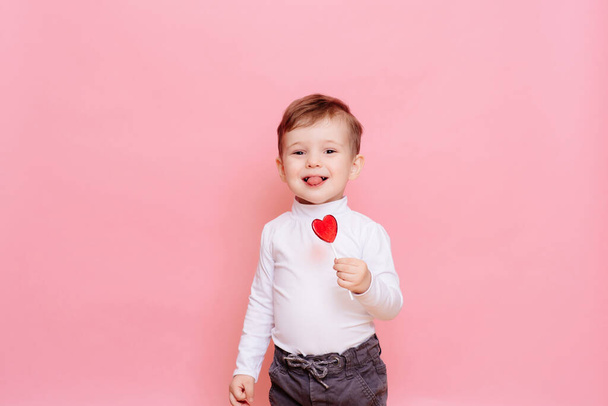 stúdió portré egy boldog fiú egy szív alakú nyalóka. - Fotó, kép