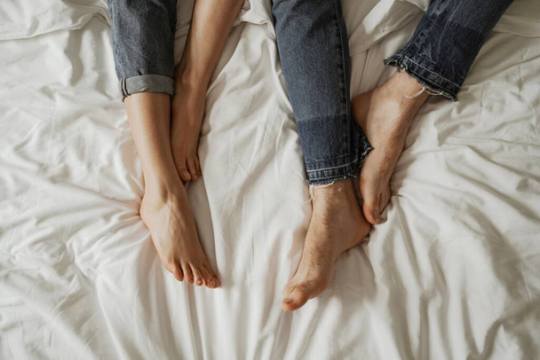 Close up legs of young couple in bad wearing jeans - Fotó, kép