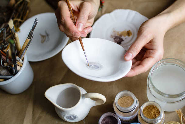 El proceso de pintar a mano una cerámica hecha a mano platos. Enfoque selectivo. - Foto, imagen