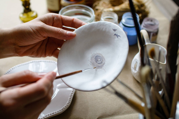O processo de pintar à mão uma cerâmica feita à mão pratos. Foco seletivo. - Foto, Imagem