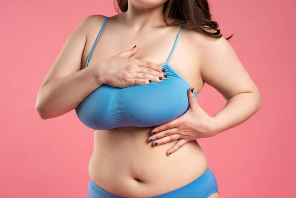 Woman checking her very large breasts for cancer on pink background, health care concept - Foto, Imagem
