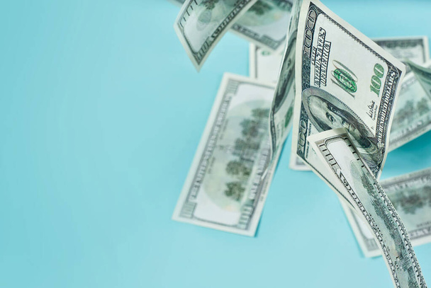 Green dollar bills on a blue background. 100 dollar bills close up. The concept of wealth and success. Money flies in the air. Copy space and free space for text near money. - Foto, Imagen