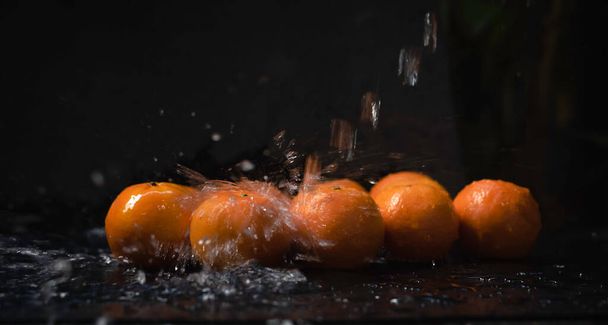 Gruppo di frutta arancione bagnata da spruzzi d'acqua, luce sfocata intorno - Foto, immagini