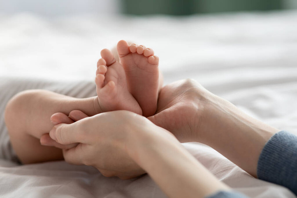 Mütter kümmern sich. Nahaufnahme Shot Of Loving Mom Holding Feet Of Newborn Baby In Hands - Foto, Bild