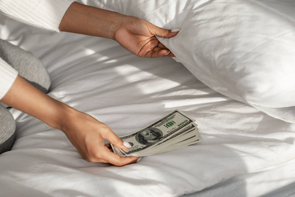 Woman hiding money under pillow at home - Photo, Image