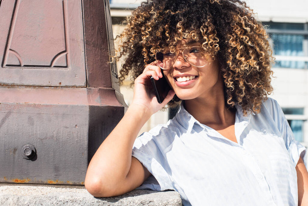 Close up portrait smiling young african American woman talking with cellphone outside - Photo, Image