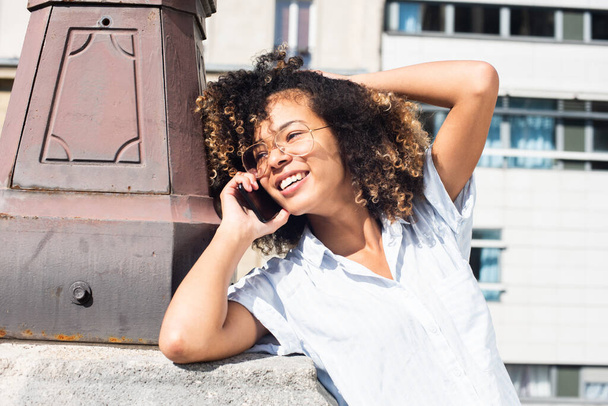 肖像画幸せな若いアフリカ系アメリカ人の女性は外で携帯電話と話して - 写真・画像