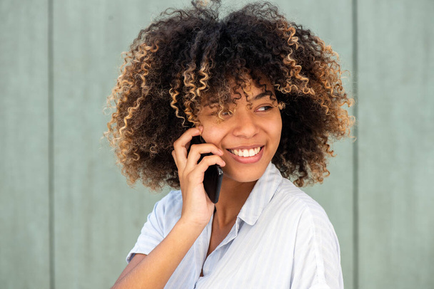 Nahaufnahme Porträt junge schwarze Frau lächelt, während sie mit dem Handy spricht  - Foto, Bild