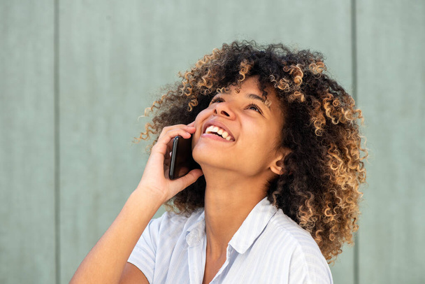 Закріпіть портрет молодої афроамериканки, яка сміється під час розмови з мобільним телефоном.  - Фото, зображення