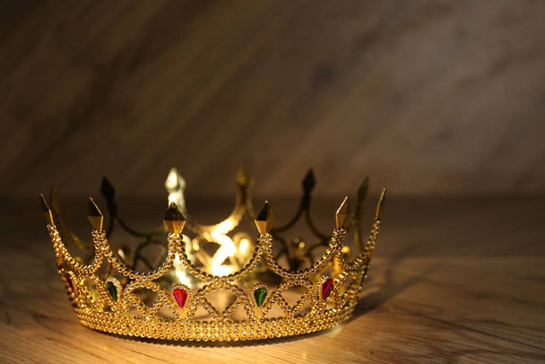 Прекрасная золотая корона с драгоценными камнями на деревянном столе, крупным планом - Фото, изображение