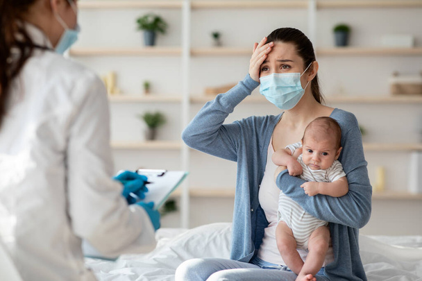 Madre en máscara protectora que sostiene al bebé recién nacido, explicando los síntomas de la enfermedad al médico - Foto, Imagen