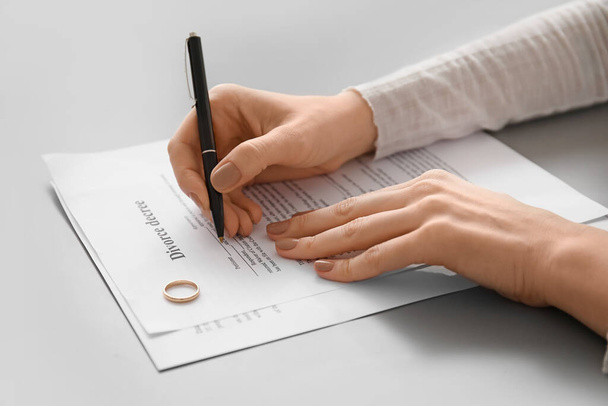 Женщина подписывает указ о разводе за столом, крупным планом - Фото, изображение