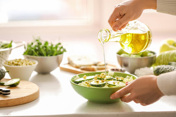 Женщина делает салат со свежими овощами на кухне - Фото, изображение