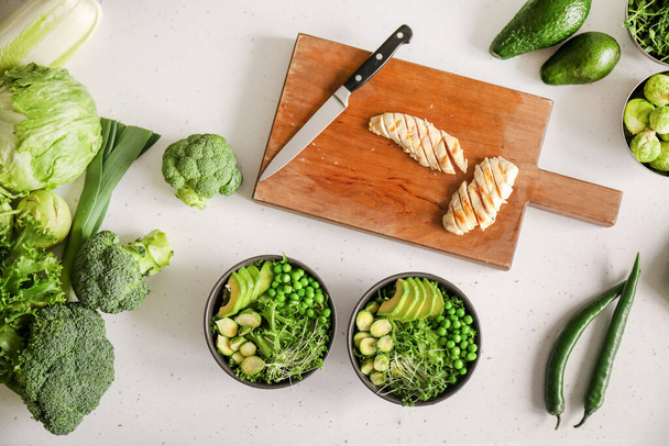 Cuencos de sabrosa ensalada con verduras frescas y pollo sobre fondo claro - Foto, imagen