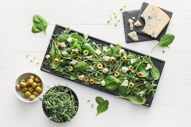 Assiette de salade savoureuse aux olives et fromage sur fond de bois blanc - Photo, image
