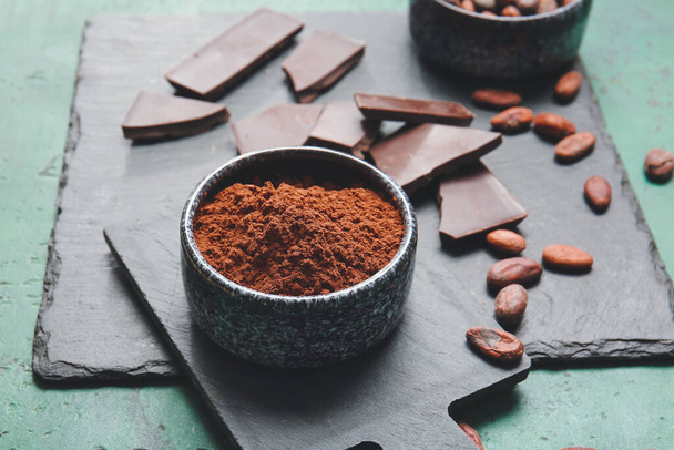 Bowl with cocoa powder and chocolate on color background - Φωτογραφία, εικόνα