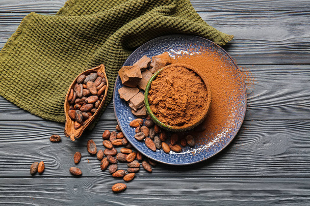 Bowl with cocoa powder and beans on dark wooden background - Photo, Image