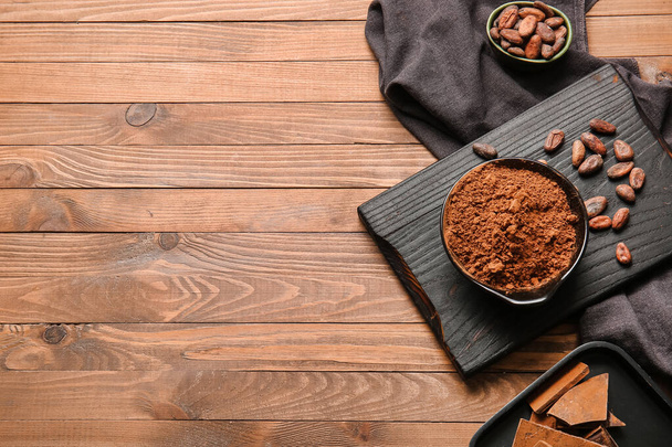 Cuenco con cacao en polvo y frijoles sobre fondo de madera - Foto, Imagen