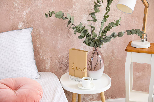 Table de chevet avec vase et tasse de café près du mur de couleur dans la chambre - Photo, image
