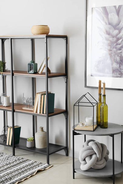 Modern shelf unit with books and table near white wall in room - Foto, Imagem