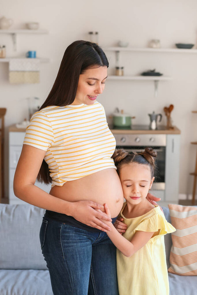 Young pregnant woman with her daughter at home - Foto, Imagen