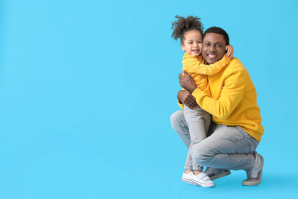 Porträt eines glücklichen afroamerikanischen Vaters und seiner kleinen Tochter auf farbigem Hintergrund - Foto, Bild