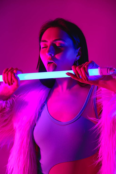 Ritratto tonico di bella giovane donna con lampada al neon su sfondo a colori - Foto, immagini
