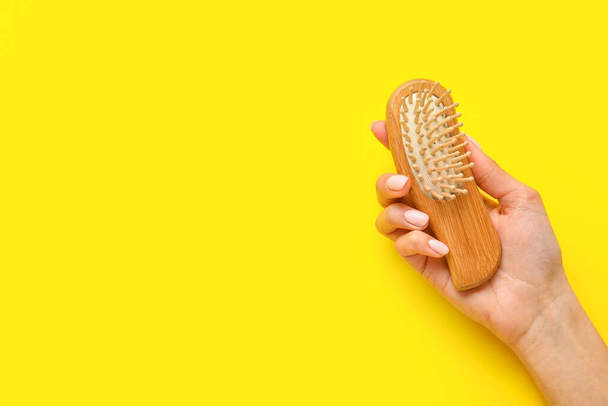 Female hand with wooden hair brush on color background - Foto, Imagem