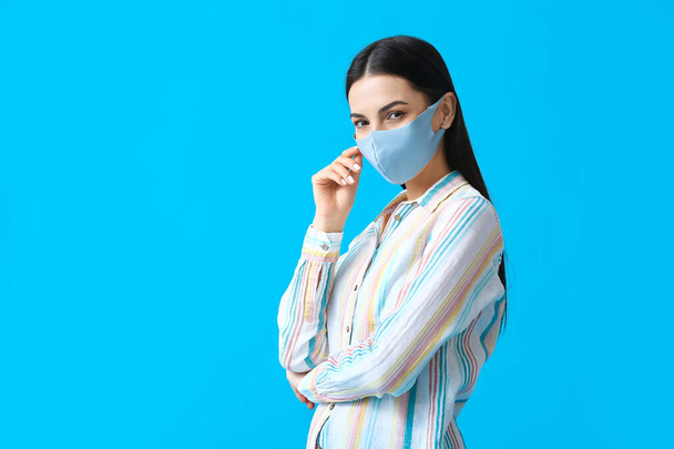 Stijlvolle jonge vrouw dragen masker op kleur achtergrond - Foto, afbeelding