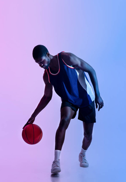 Retrato de cuerpo entero de un jugador de baloncesto negro determinado jugando a la pelota con iluminación de neón - Foto, imagen