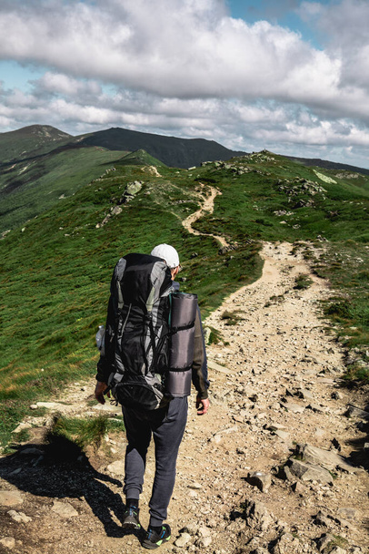 young hiker man in mountains. summer trekking path. copy space. - Foto, Imagen