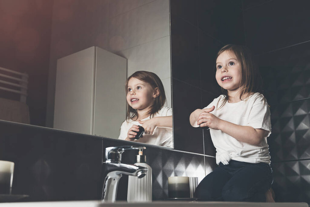 Πορτρέτο του όμορφου μικρού κοριτσιού χρησιμοποιώντας κρέμα για την περιποίηση της επιδερμίδας. . Όμορφο παιδί καθαρίζει ή ενυδατώνει το δέρμα της. προβλήματα των παιδιών, υγιεινή, καθαρό και φρέσκο δέρμα. - Φωτογραφία, εικόνα