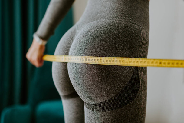 Fitness Woman Measuring butt With Tape at home. strong buttocks concept. - Photo, image