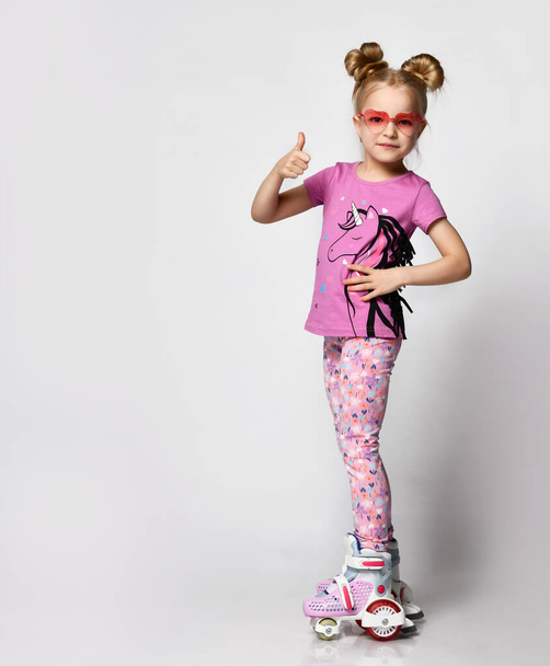 Full body portrait of funky girl learning to ride on roller skates studio shot - Foto, afbeelding