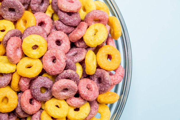 A closeup shot of breakfast cereal rings in a bowl isolated on a light blue  background - Fotó, kép