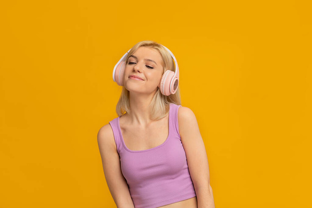 Ωραίος ήχος. Ενθουσιασμένη κυρία φορώντας ασύρματα ακουστικά, ακούγοντας μουσική με κλειστά μάτια - Φωτογραφία, εικόνα