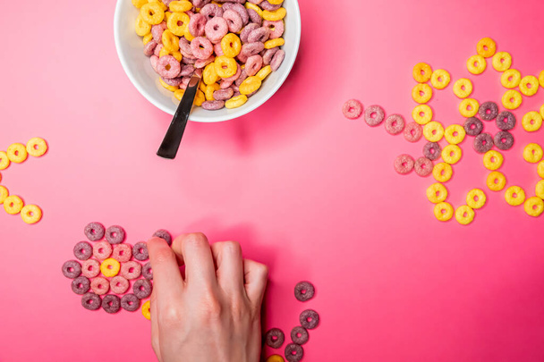 A top view of a bowl with crunchy cereal on a pink surface - Photo, Image