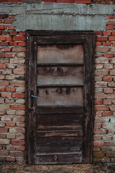 A vertical shot of an old wooden door of a stone building - Fotoğraf, Görsel