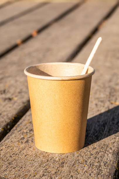 A vertical shot of a brown paper cup with a stick on a wooden surface - Fotoğraf, Görsel