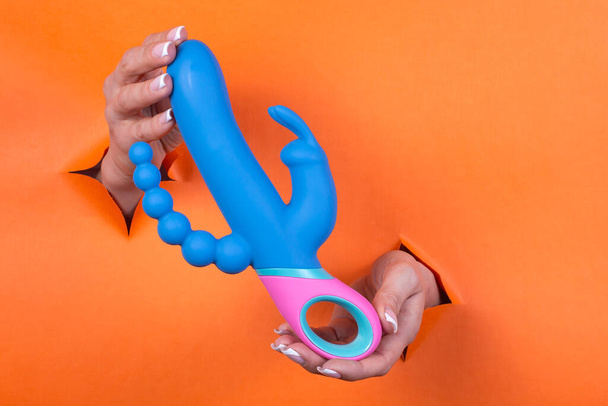 Adult sex toys in beautiful female hands on an orange background. Toys for adult women. - Foto, immagini