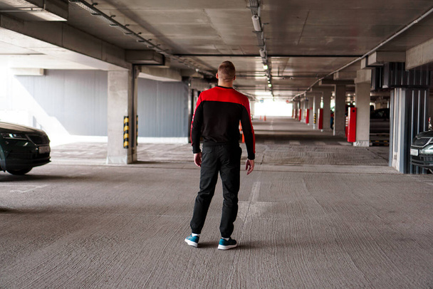 A young man in a sports uniform in an underground parking lot. - Valokuva, kuva