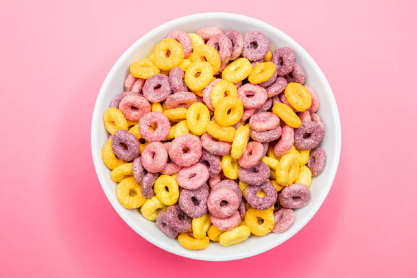A closeup shot of breakfast cereal rings in a bowl isolated on a pink background - Photo, image