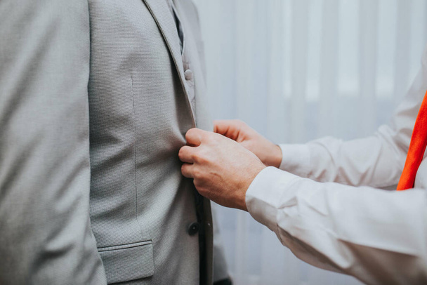 A shallow focus of a man helping to button the coat of the groom - Foto, imagen