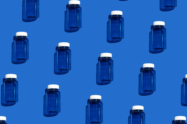 Medikamentenglasmuster. Modisches blaues Medikamentenglas auf hellblauem Hintergrund. Buntes Muster. Blick von oben - Foto, Bild