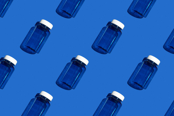 Medicijnpot patroon. Modieuze blauwe medicijnpot op een helderblauwe achtergrond. Kleurrijk patroon. Uitzicht van bovenaf - Foto, afbeelding