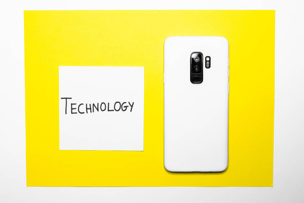 A closeup shot of a white smartphone on a yellow paper surface - Photo, image