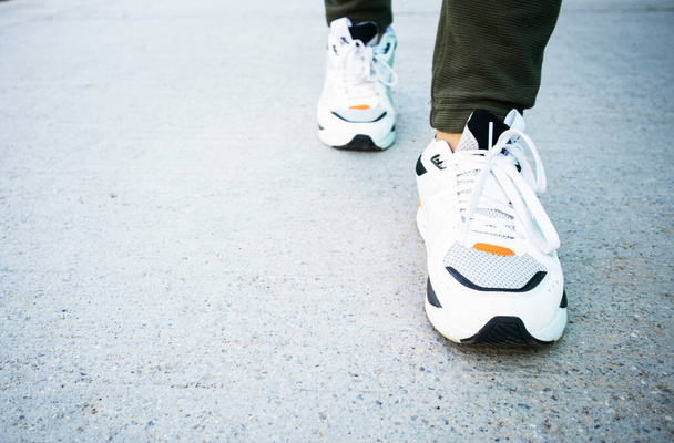 A személy futócipőt visel a gyalogláshoz és a futáshoz az út hátterén.Egészségügyi gyakorlat koncepció. - Fotó, kép
